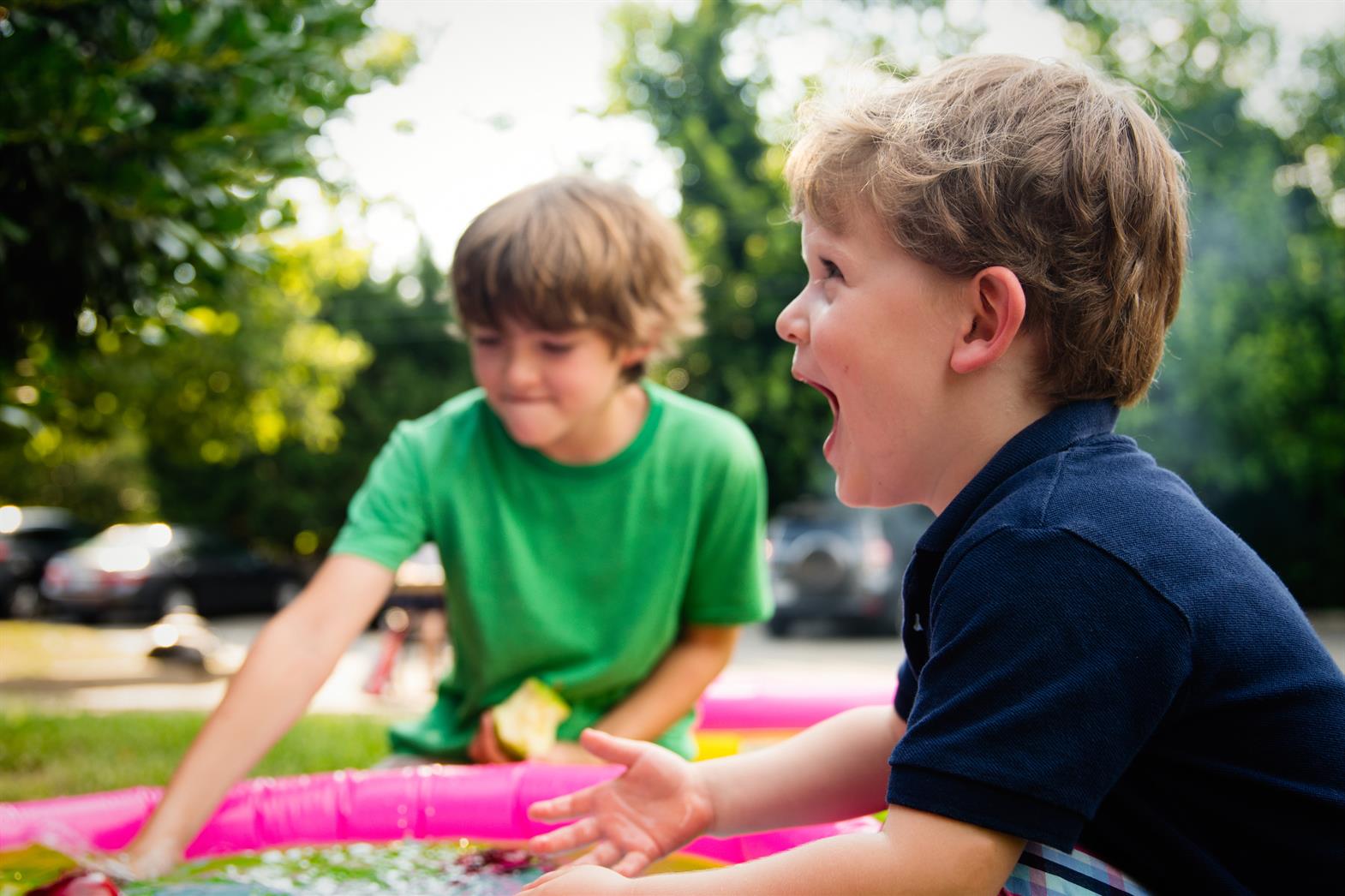 two young boys playing with a large pink tube and laughing