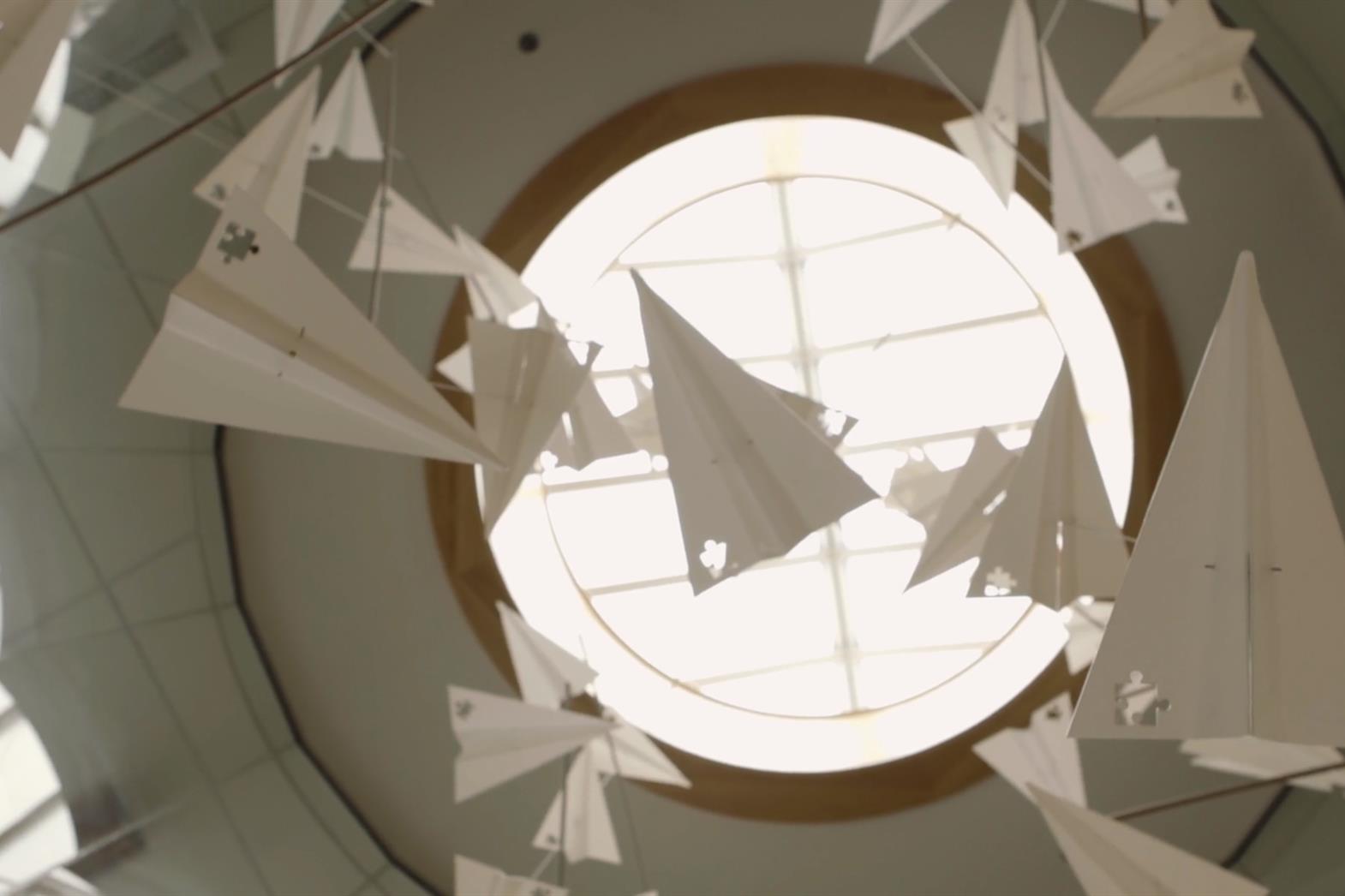 many paper airplanes floating in front of a round window