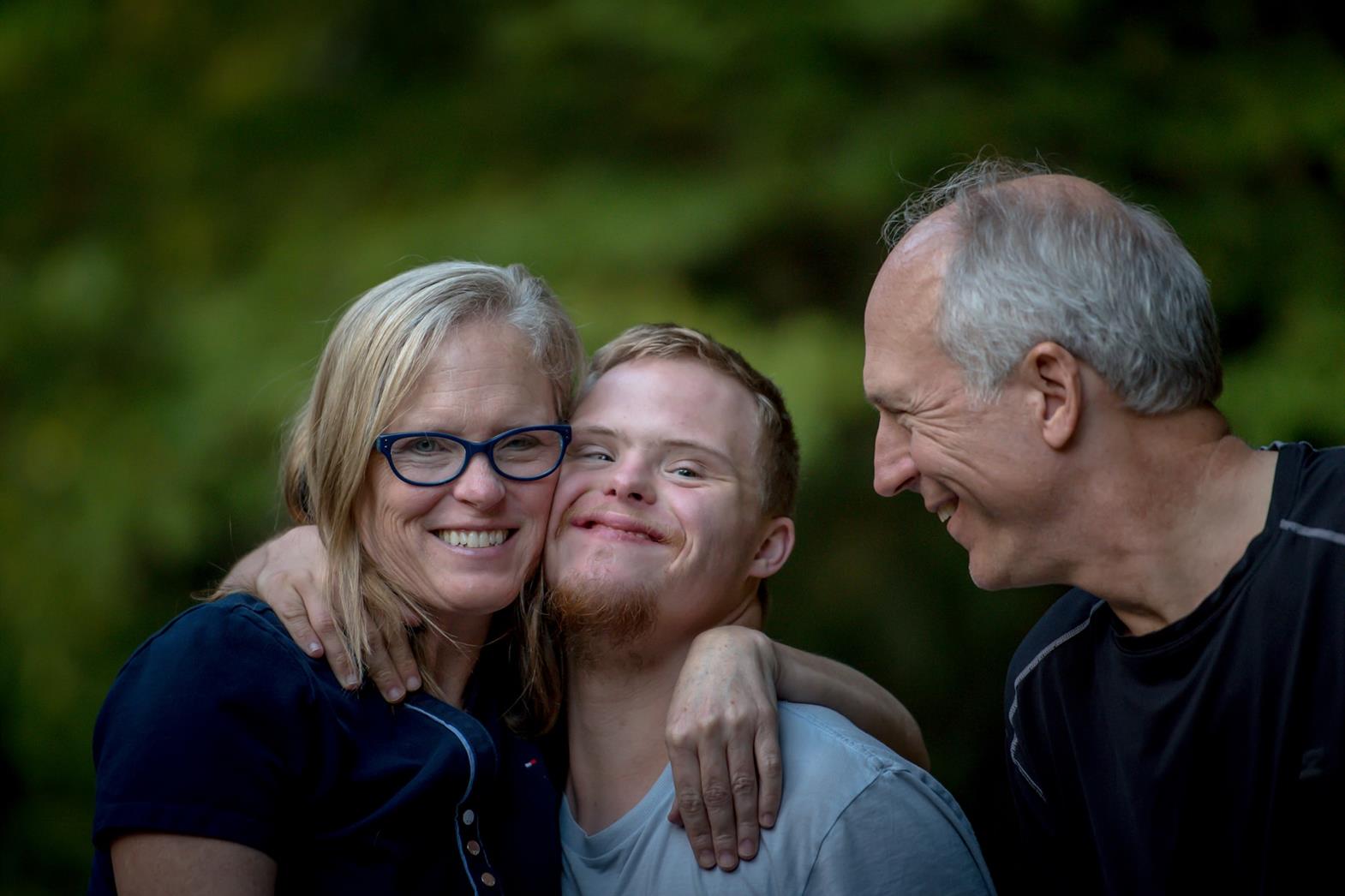 Three people standing close together and smiling