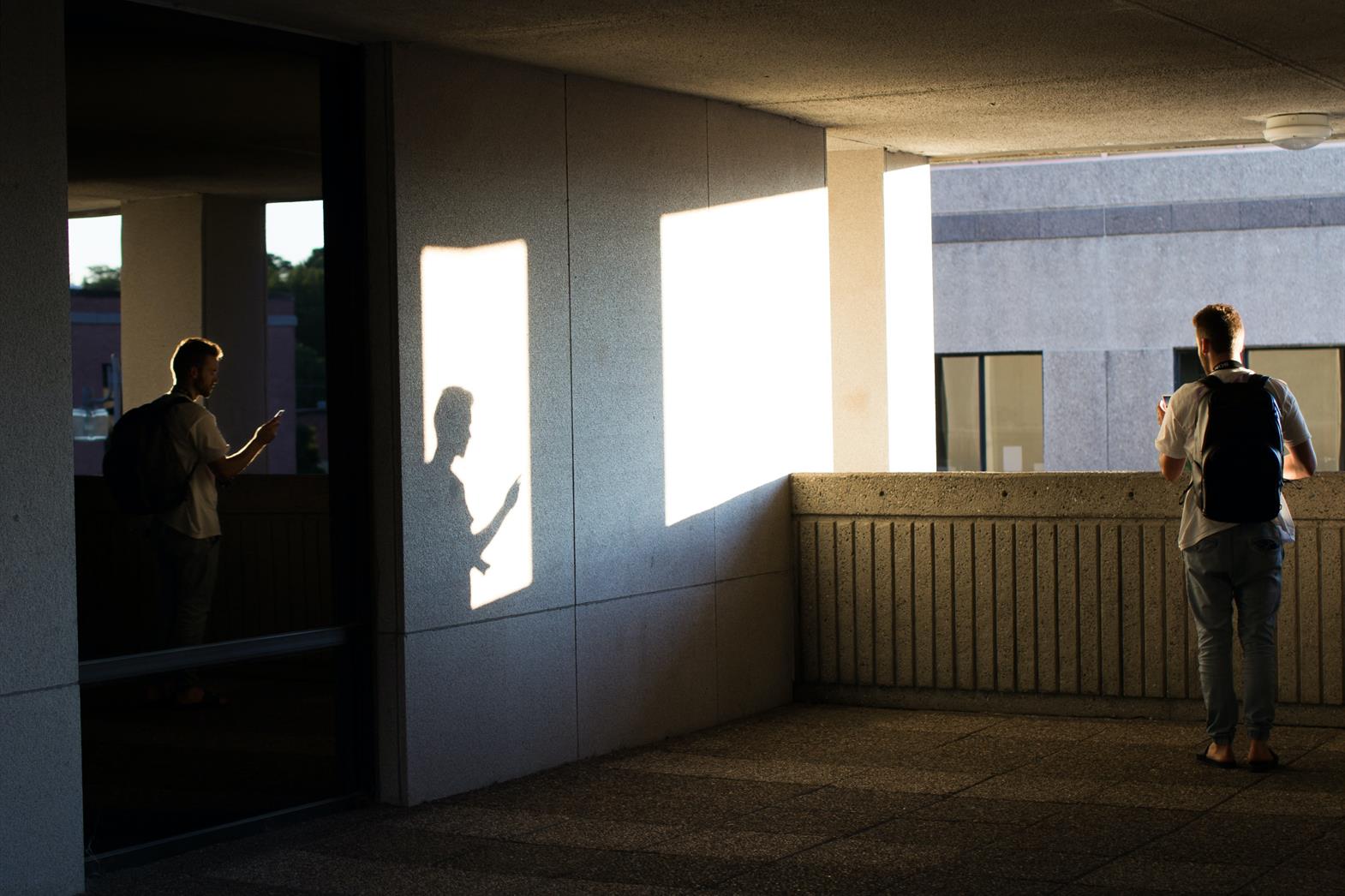 Teen standing looking out over a balcon with his back to the camera