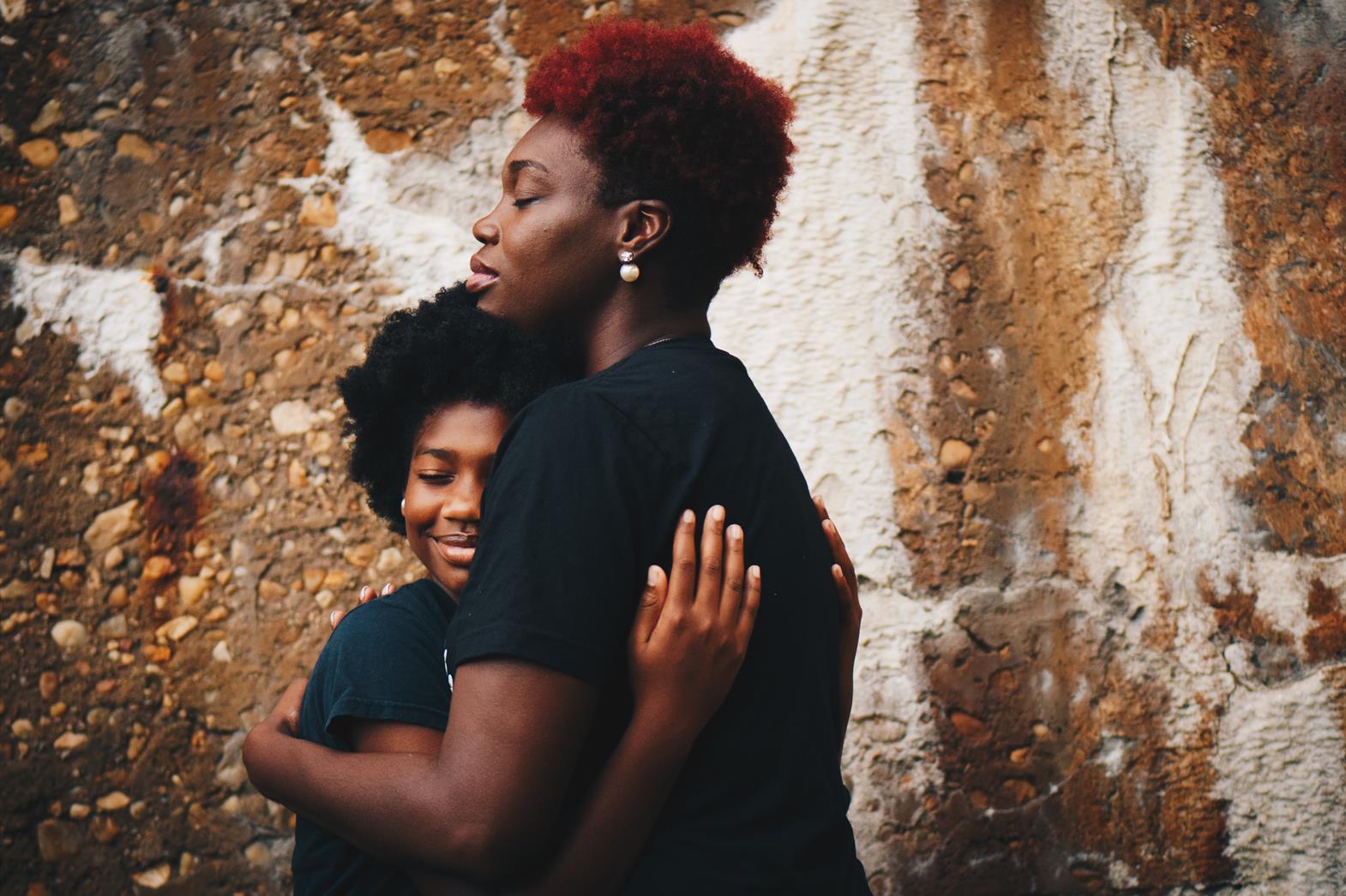 Mother and daughter of colour hugging