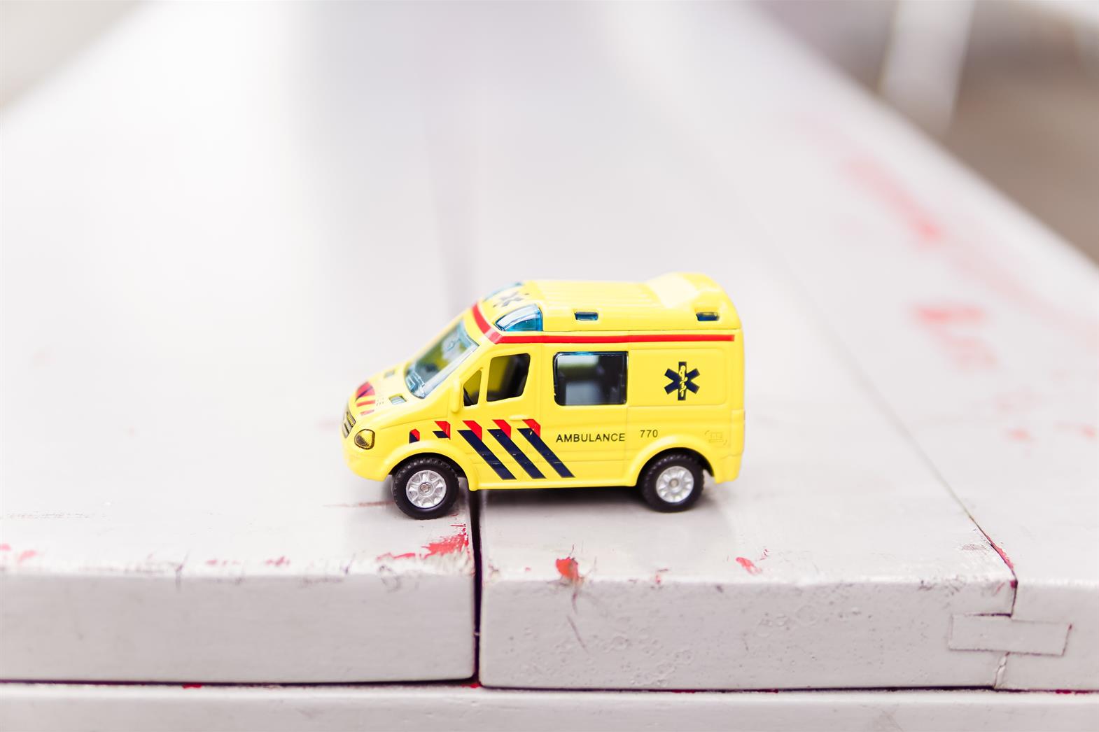 Toy ambulance sitting on a wodden bench