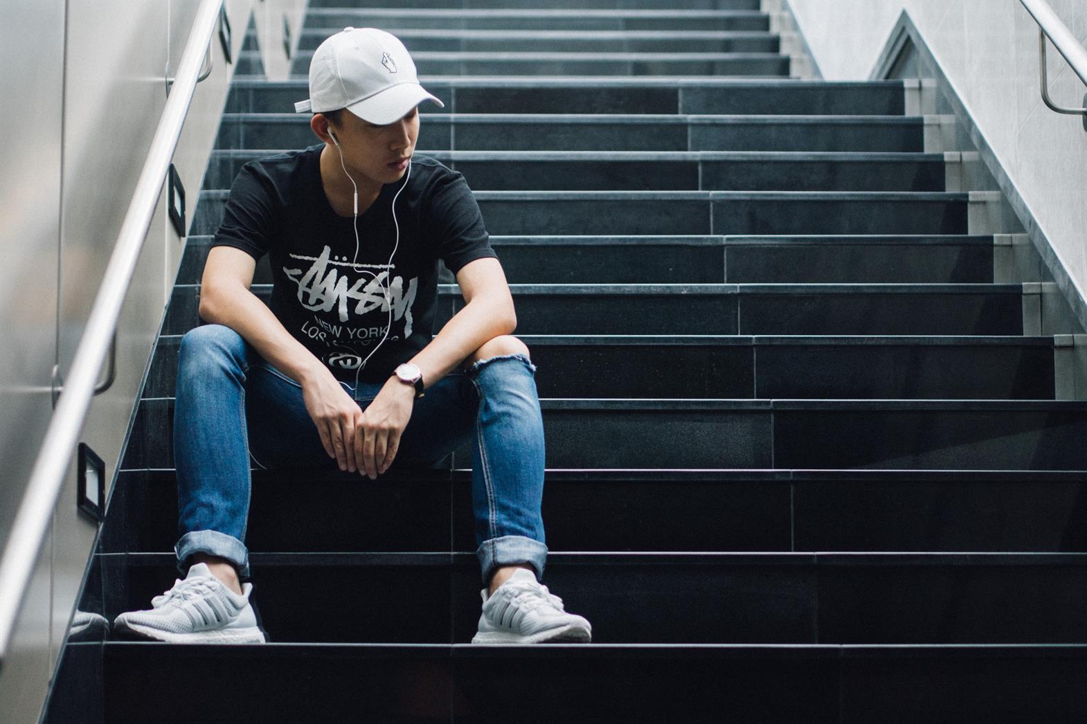 Young man sitting on stairs alone frowning