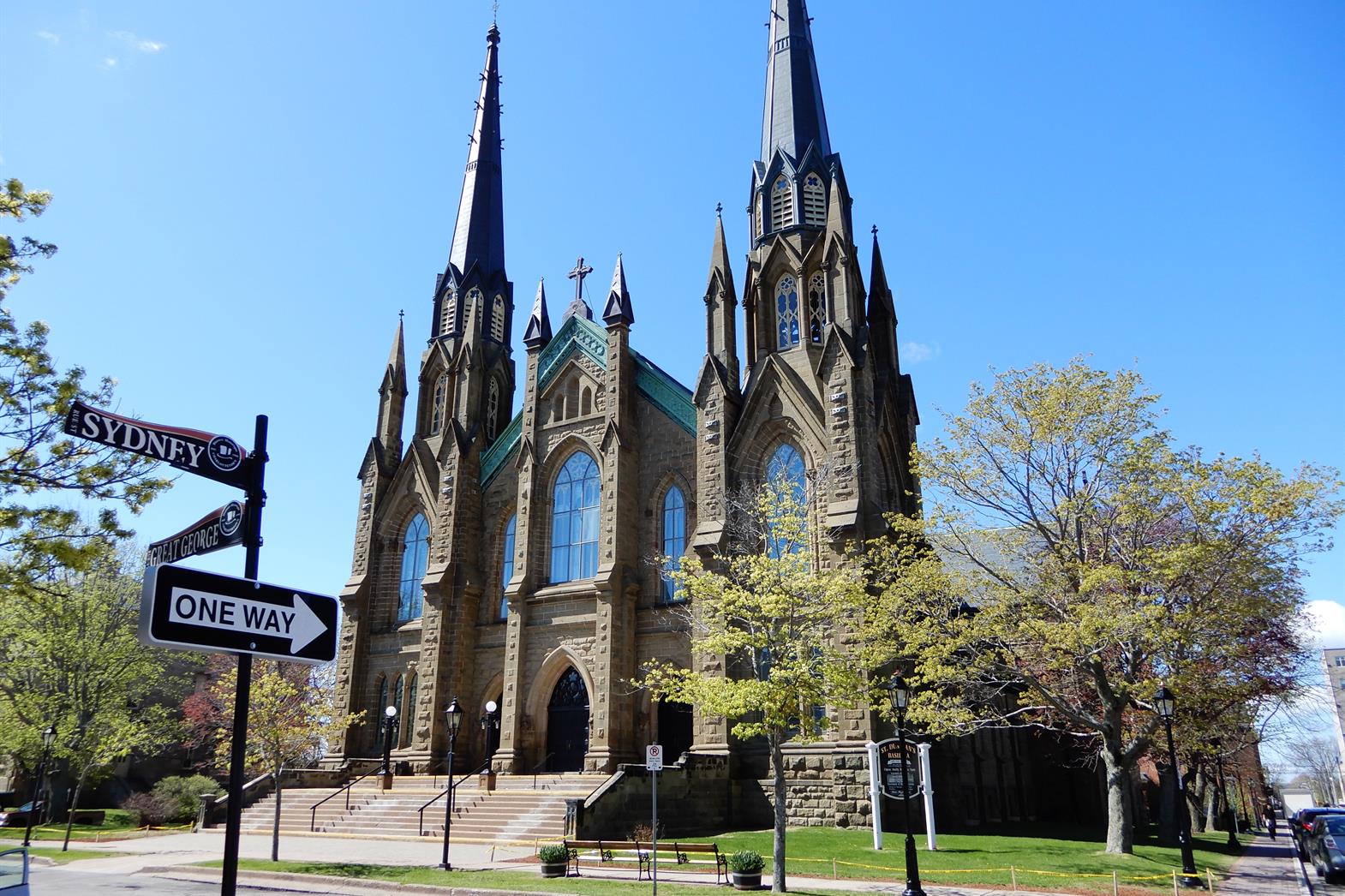 A stone church on a spring day in Charlottetown PEI. Blue skies in the background. A one was sign post in the foreground.