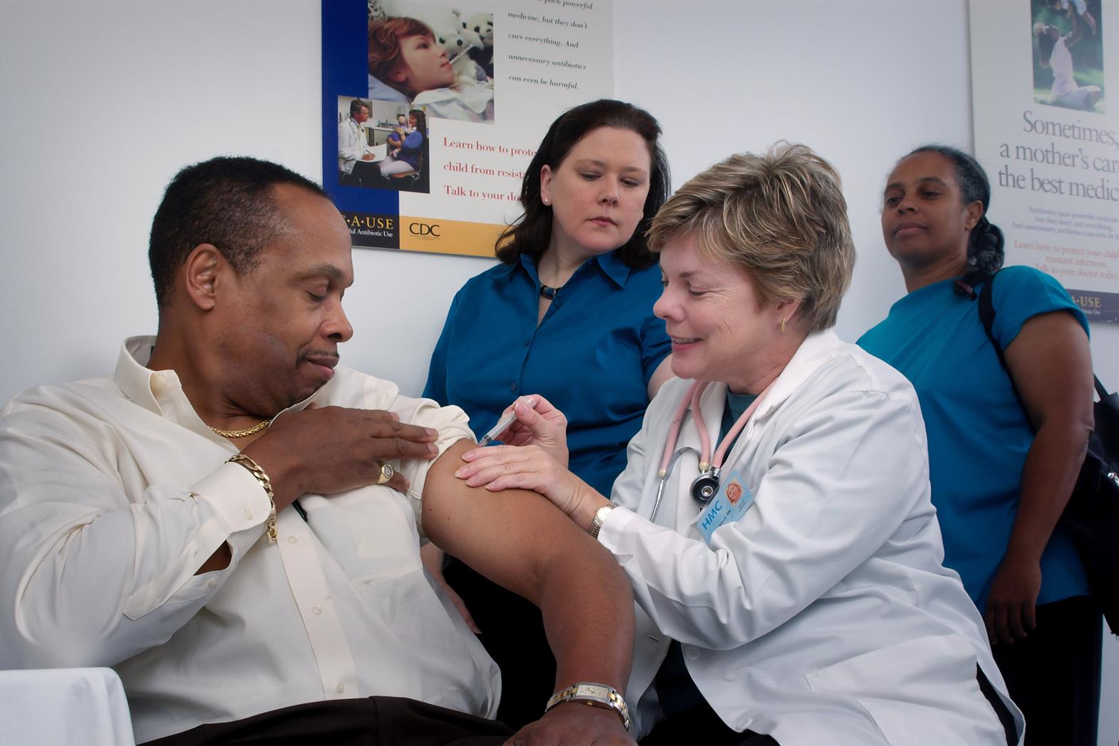 a nurse administeres a needle to a man who is sitting in a chair