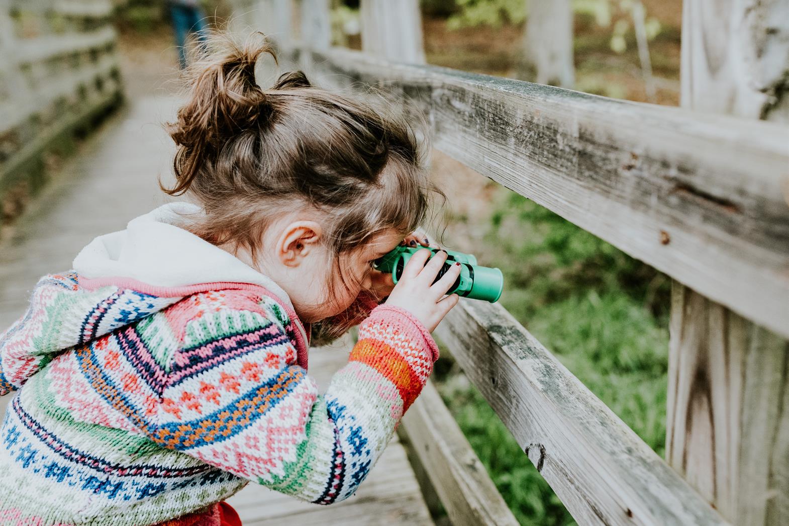 Child looking through toy binoculars